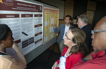 Attendees looking at researcher poster
