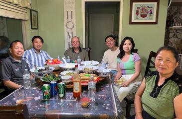 Tou Thao and his family and Robert Straka are seated at a table looking at the camera and smiling.